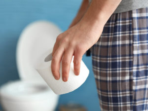 Man in bathroom with a roll of toilet paper in his hand